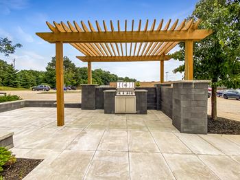 an outdoor kitchen with a wooden pergola on top of a stone patio